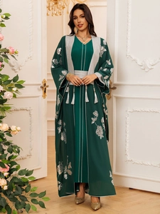 Détail de robe vert foncé avec broderie florale argentée, paillettes et pompon décoratif