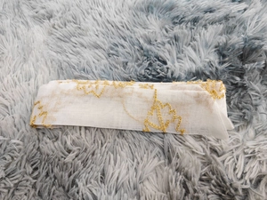 Close-up of white mesh fabric with intricate gold floral vine embroidery and metallic thread