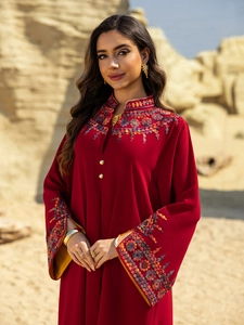 Close-up of floral embroidery on a deep red kaftan dress with gold button details