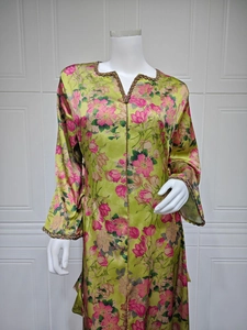 Detail of V-neck printed kaftan dress featuring pink floral patterns and gold beaded trim