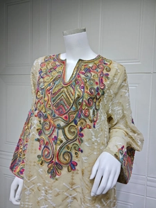 Detail of complex floral embroidery and sequins on a beige mesh ethnic tunic dress