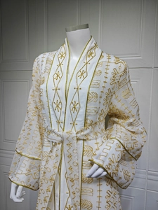 Détail d'une robe en tulle blanc avec broderies dorées et perles de style caftan