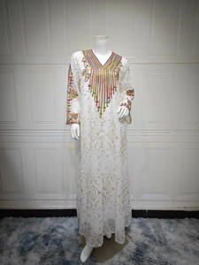Détails de broderie colorée et de paillettes dorées sur les manches de la robe de soirée