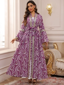 Dettaglio di ricamo e paillettes su un caftano floreale viola con maniche lunghe e cintura