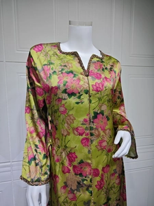 Close-up of V-neckline with metallic trim on floral green long sleeve caftan dress