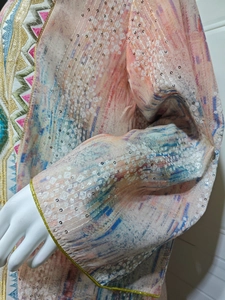 Détail d'une robe ethnique montrant des paillettes argentées et une broderie géométrique