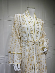 Détail d'un kaftan blanc élégant avec broderies dorées complexes et finitions de qualité