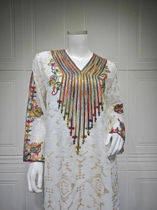 Détail de broderies perlées colorées et dorées sur une robe de soirée blanche