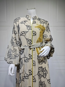 Detailed close-up of golden sequin embroidery and black maple leaf print on Jalabiya dress