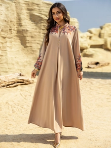 Detail of multi-color floral embroidery on a beige boho maxi dress with gold buttons