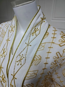 Détail de broderie dorée et perlage sur une robe caftan blanche élégante en maille filet