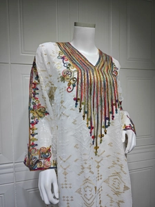 Détails de broderies bohèmes et de paillettes sur une robe de soirée blanche à décolleté en V