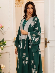 Détail de la broderie florale argentée et paillettes sur une robe vert foncé fluide