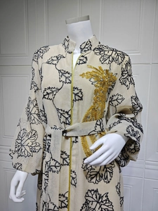 Detail of gold sequin embroidery and black leaf print on a beige Jalabiya maxi dress