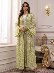 Dettaglio dell'Abaya verde chiaro con ricami dorati e motivi floreali bianchi