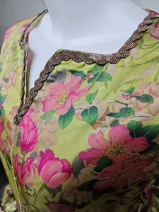 Detail of V-neckline with sparkling sequins and rhinestone trim on green floral dress