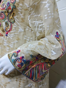 Macro detail of intricate embroidery and multi-colored beadwork on mesh sleeve