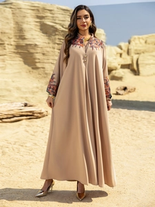Detailed view of colorful floral embroidery on an elegant beige abaya maxi dress