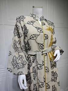 Detailed view of beige Jalabiya with black leaf embroidery and gold tassel brooch