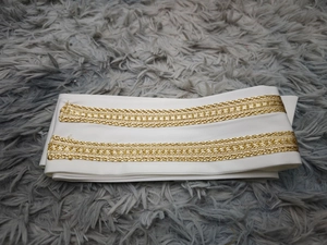 Nahaufnahme des weißen Stoffgürtels mit zwei goldenen Stickborten und Metalldetails