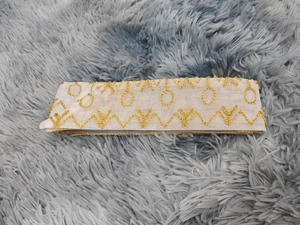 Détail de la broderie élégante en maille et des perles dorées sur la taille de la robe