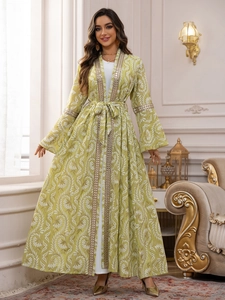 Dettaglio del set abaya verde chiaro con ricami dorati e abito interno bianco lungo
