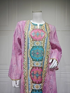 Détail d'un caftan rose avec broderies florales complexes et finitions pailletées