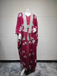 Détail d'abaya bordeaux avec broderies florales argentées et pompons élégants en gros plan
