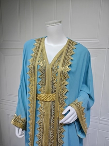 Macro view of gold embroidery and sequin detail on light blue chiffon kaftan dress