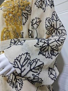Detailed view of intricate gold embroidery and black sequins on a cream jalabiya dress