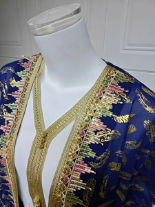 Gros plan détaillé du caftan bleu foncé avec imprimé plumes dorées et broderie pailletée