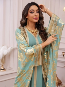 Close-up of gold sequin embroidery and floral lace on a mint green kaftan dress