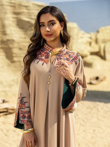Detail of colorful floral embroidery on the neckline and cuffs of a beige kaftan dress