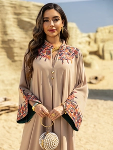 Close-up of colorful floral embroidery on neck and cuffs of beige ethnic abaya dress