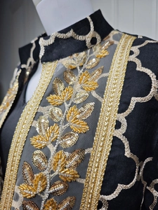 Detailaufnahme der aufwendigen goldenen Pailletten-Stickerei auf einem schwarzen Maxikleid