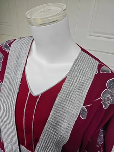 Détails de broderie florale à paillettes argentées sur une robe ethnique bordeaux