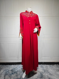 Detail of floral embroidery and gold buttons on a red long-sleeved kaftan dress