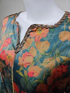 Detail of V-neckline with golden sequins and floral print on soft green fabric