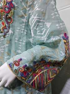 Close-up of intricate white embroidery and sequins on light mint green mesh dress