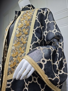 Nahaufnahme der goldenen Blattbestickung und Pailletten auf einem schwarzen langen Cardigan