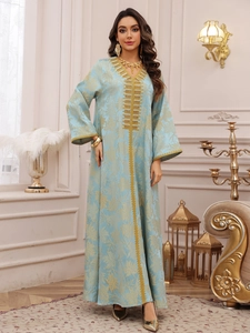 Detail showing golden leaf jacquard and intricate embroidery on a blue kaftan dress