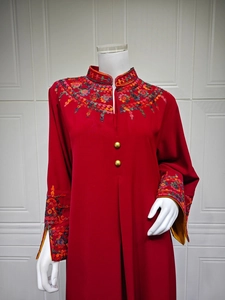 Detail of red floral embroidery on high-neck maxi dress with metallic buttons