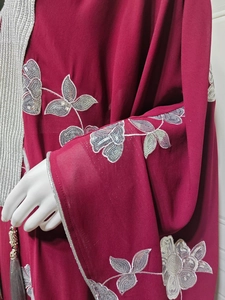 Détail du caftan bordeaux avec broderie de paillettes argentées et pompons gris déco