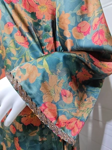 Detailed view of the beaded trim and floral print on the sleeve of the dark green dress