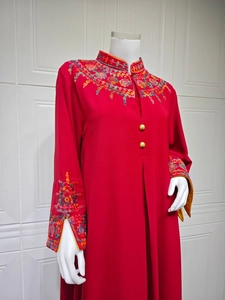 Detailed close-up of intricate floral embroidery and gold buttons on red dress