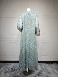 Detail of mint green kaftan with white geometric patterns and ethnic floral embroidery