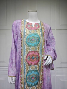 Gros plan sur les broderies roses et dorées d'une robe caftan violette à manches longues