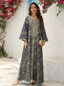 Close-up of golden baroque embroidery on a navy evening kaftan dress with trumpet sleeves