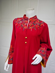 Detail of red dress featuring intricate floral embroidery and golden buttons on collar
