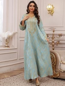Détail de la robe caftan bleu clair avec broderie florale dorée et bordures tressées dorées